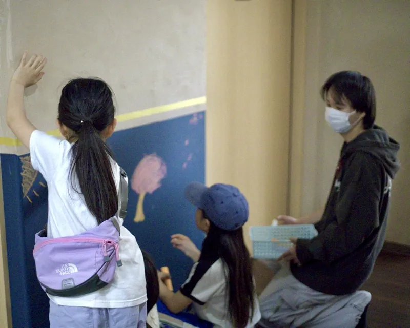 子どもたちが施設の壁に絵を描いている様子