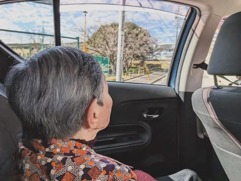 車の窓から外の景色をながめるご入居者の後ろ姿