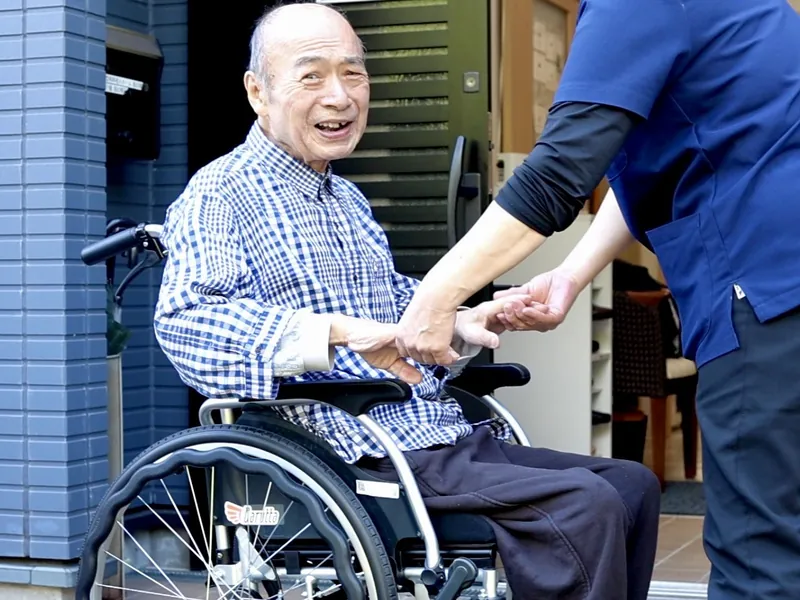 施設の玄関先で職員と手を取り合うご入居者