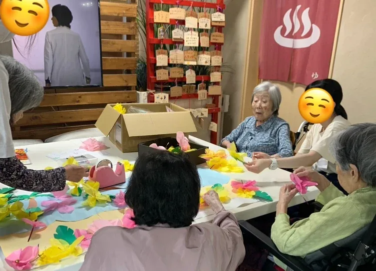 職員と一緒に、紙の花の飾りをつくるご入居者